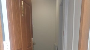 Un couloir avec une porte en bois, un radiateur et un sol recouvert de moquette.