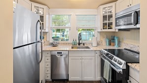 A modern kitchen with white cabinets, stainless steel appliances, a dishwasher, and a stove. - Secret Garden @ Seminole located in the heart of downtown Stuart, FL (Stuart)
