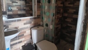 A bathroom with a tiled wall, a toilet, a sink, and a shower curtain.