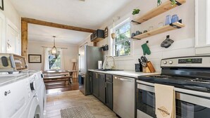 Una cocina moderna con lavadora integrada, vigas de madera y salpicadero de piedra.