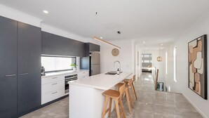 Una cocina moderna con una isla grande, taburetes de bar y vista al área de comedor.