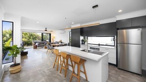 Una cocina moderna con una isla central, electrodomésticos de acero inoxidable y un comedor con taburetes de bar.