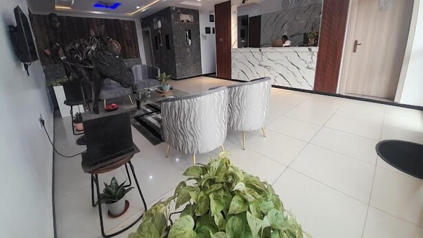 A modern hotel lobby with a reception desk, seating area, and a large potted plant. - Klulead Garden and Suites (Ijebu Ode)