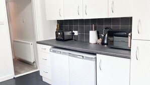 Una cocina moderna con armarios blancos, encimera negra y lavavajillas.