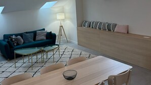 A loft-style room with a high ceiling, exposed wooden beams, a dining area with a table and chairs, a sofa, and a bench. - LYON Bellecour quiet area near fabric museum - ideal for families  (Lyon)