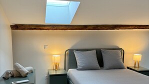 A bedroom with a skylight, a bed, two bedside tables with lamps, and a nightstand with a remote control. - LYON Bellecour quiet area near fabric museum - ideal for families  (Lyon)