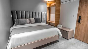A modern bedroom with a large bed, a bedside table, a mirror, and an air conditioning unit.