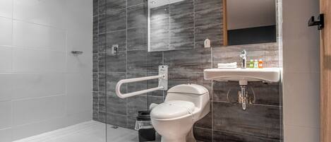 Un baño moderno con cabina de ducha de vidrio, inodoro blanco y lavamanos con espejo.