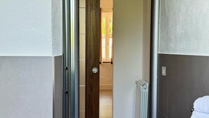 Un baño moderno con un lavamanos blanco, una toalla y una puerta de madera que da a un pasillo.