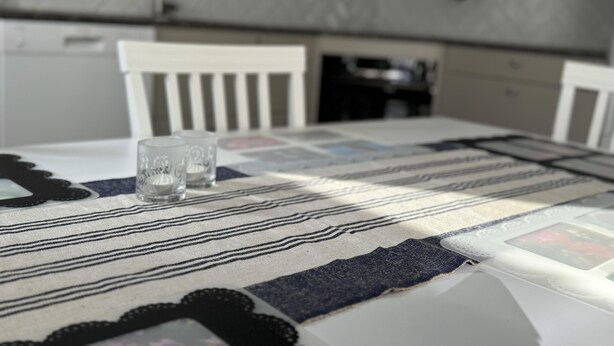 A kitchen with a table set for two, featuring a patterned tablecloth and two glasses. - In the Middle of the Forest Nearby Ahus (Aahus)