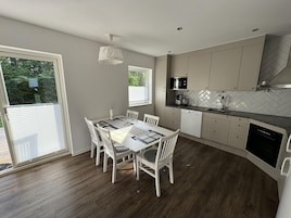 A modern kitchen with white cabinets, a herringbone backsplash, and a dining area with a white table and chairs.