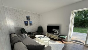 A modern living room with a sofa, chairs, a coffee table, and a TV. - In the Middle of the Forest Nearby Ahus (Aahus)