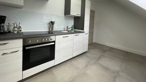 Una cocina moderna con armarios blancos, un horno negro y una campana extractora de acero inoxidable.