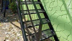 A metal staircase with a green textured wall beside it. - Departamento cerca del centro (El Calafate)