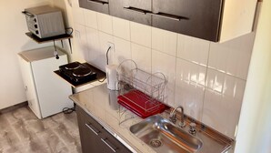 A compact kitchen with a built-in oven, a sink, and a small refrigerator. - Departamento cerca del centro (El Calafate)