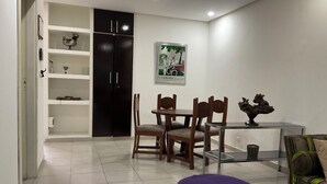 Een moderne woonkamer met een eethoek, met een bank, stoelen, een bijzettafeltje en een paars poef.