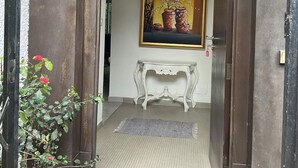 Een deur die leidt naar een kamer met een schilderij, een witte console en een potplant.