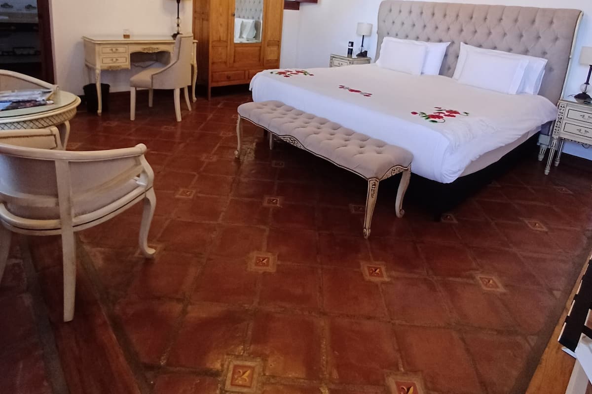 Un dormitorio con una cama grande, un armario de madera, un escritorio y una silla.