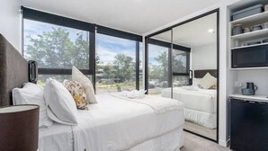 Une chambre à coucher moderne avec un grand lit, une table de chevet et un téléviseur intégré.