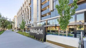 Un bâtiment moderne avec une enseigne indiquant « Midnight » et un chemin menant à l’entrée.