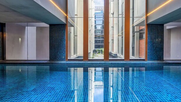 A modern indoor swimming pool with a clear view of the outside buildings through large windows. - Little Midnight 1 in the heart of town (Braddon)