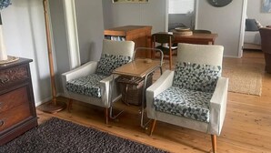 A living room with two armchairs, a small table, and a floor lamp. - Cosy retro styled bungalow (Mollymook Beach)