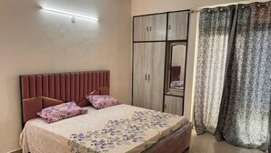 A bedroom with a bed, a wardrobe, a mirror, and curtains. - Highriseviews/familyfriendly/neartajmahal (Agra)
