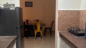 A kitchen with a refrigerator, a dining table with chairs, and a tiled backsplash. - Highriseviews/familyfriendly/neartajmahal (Agra)