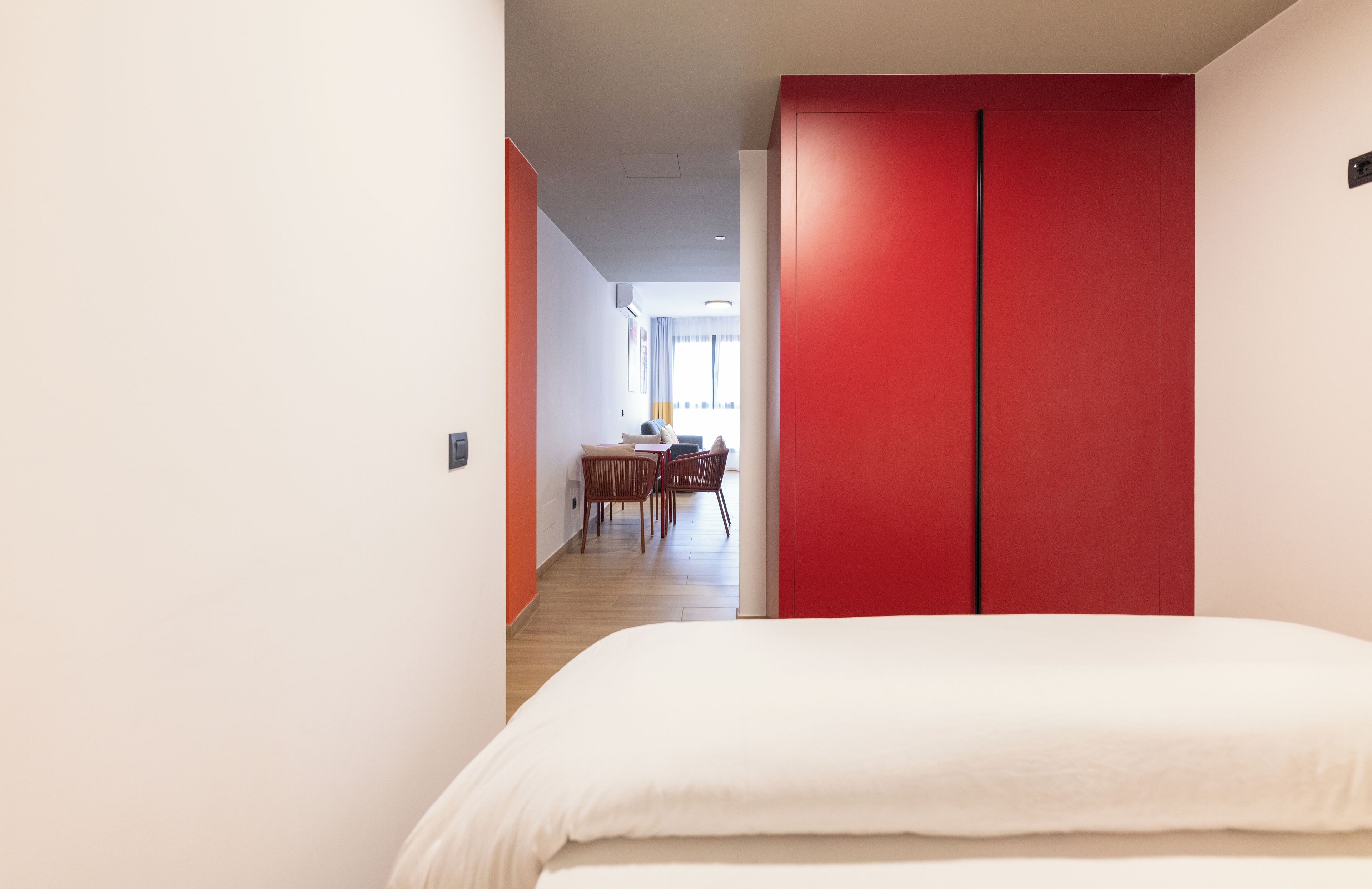 Ein Hotelzimmer mit einem großen Bett, einem roten Kleiderschrank und einem Essbereich im Hintergrund.