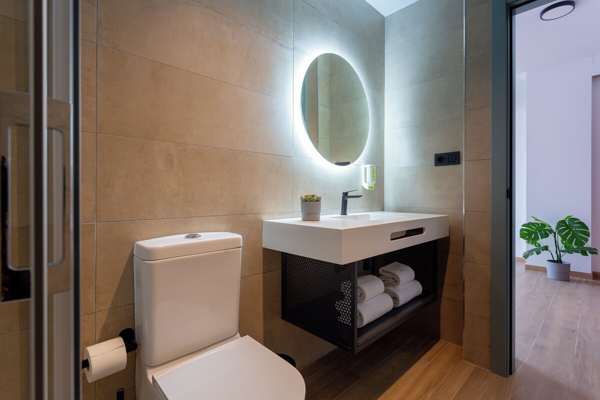 Un baño moderno con inodoro, lavabo y espejo.