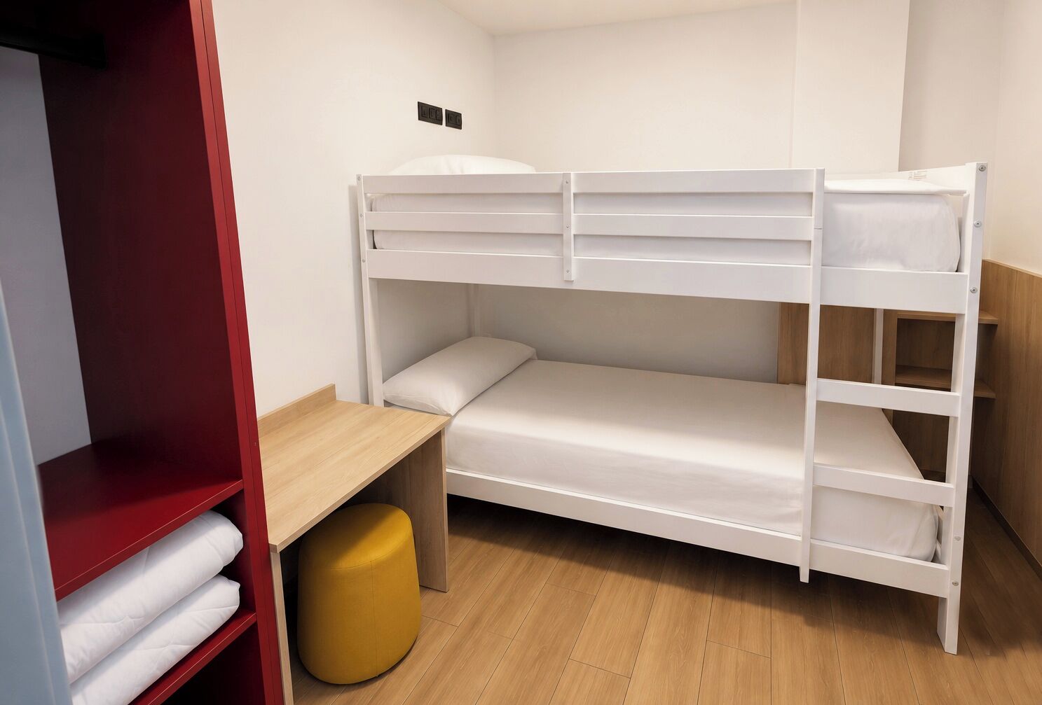 Una cama litera con escritorio y armario en una habitación.
