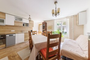 A modern kitchen with wooden cabinets, a dining table, chairs, and a built-in oven.