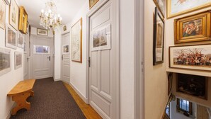 A hallway with white doors, framed pictures, and a chandelier. - L'Arverne du Rocher - Maison vue montagne (La Bourboule)