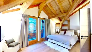 A bedroom with a large bed, a chair, and a view through a glass door.