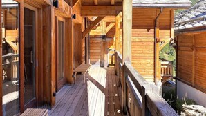 A wooden balcony with a wooden bench, wooden railings, and a clear view of the surrounding landscape.