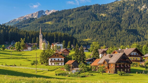 En landlig landsby med traditionelle huse, en kirke og et bjerg i baggrunden.
