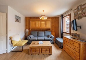 A cozy living room with a sofa, a yellow chair, a wooden coffee table, and a TV on a wooden cabinet. - CASA-Amélie terrasse, vue & parking (Vars)
