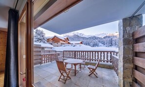 Un balcon avec vue sur des montagnes enneigées et un chalet en bois.