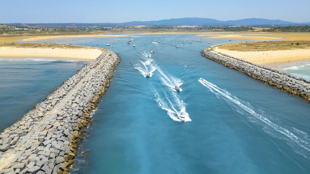 Een rivier met bootjes, omringd door rotsen en zandstranden.