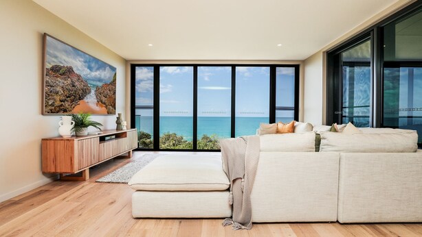 Ein geräumiges Wohnzimmer mit einem großen Fenster und Blick auf das Meer.