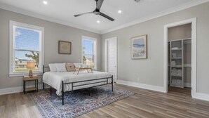 A bedroom with a bed, a ceiling fan, a window, and a walk-in closet.