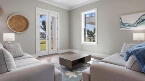 A modern living room with a grey sofa, a coffee table, and a large window.