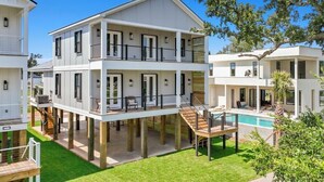 A multi-story house with a balcony, a pool, and a well-maintained lawn.