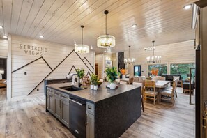 Eine moderne Küche mit einer zentralen Kochinsel, Holzböden und Pendelleuchten.