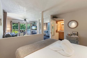 A hotel room with a bed, a dresser, a mirror, and a view of the outside.