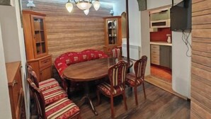 Un coin repas avec une table et des chaises en bois, un lustre et des placards encastrés en bois.