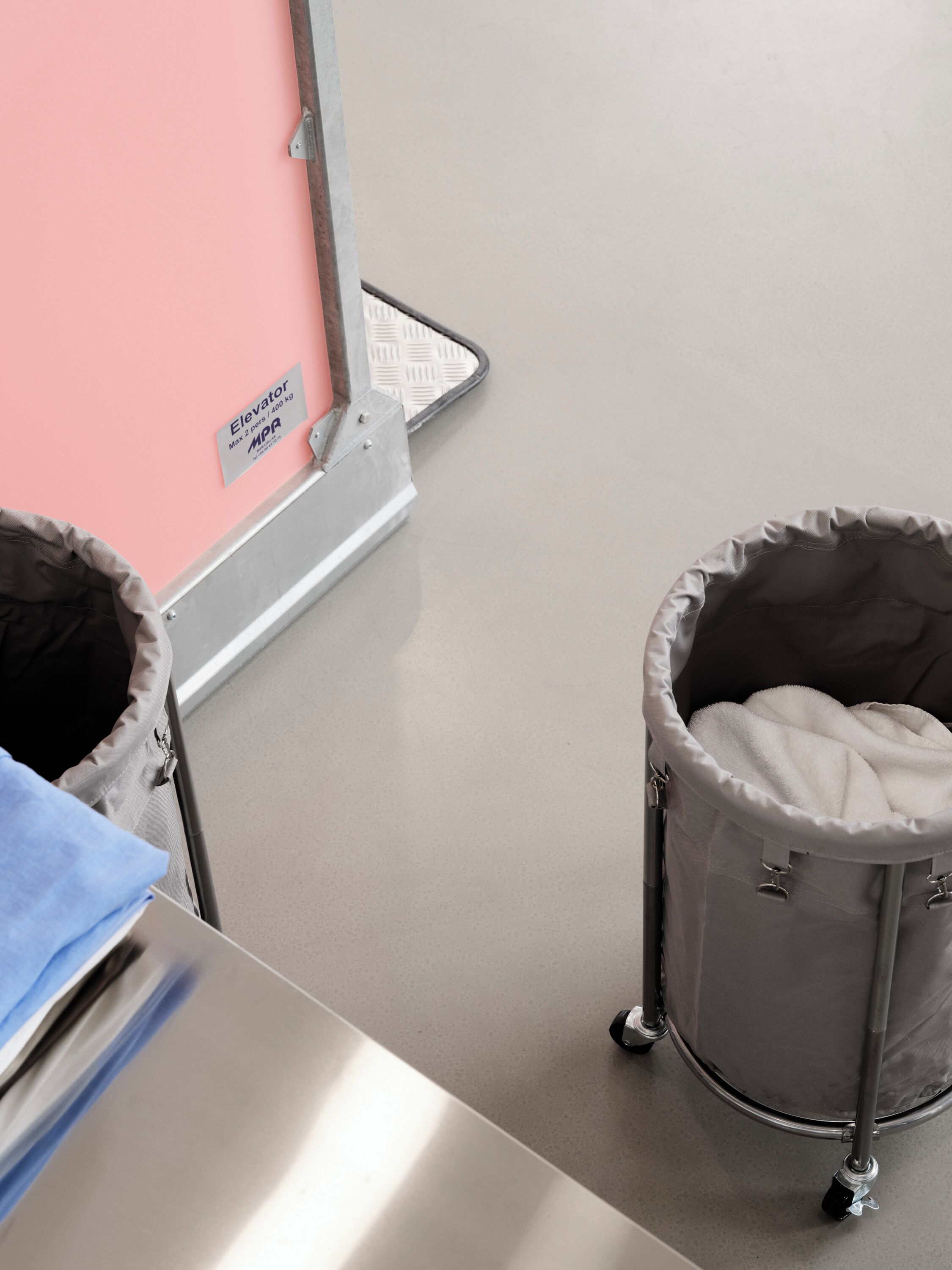 A baby changing station with a pink wall and a metal frame.