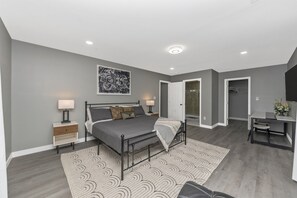 A modern bedroom with a bed, bedside tables, a desk, and a chair.