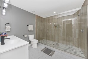 A modern bathroom with a glass-enclosed shower, a white sink, and a toilet.
