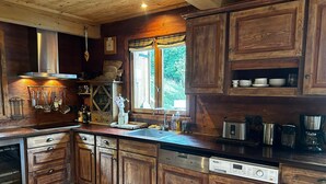 A rustic kitchen with wooden cabinets, a stainless steel range hood, and a dishwasher. - Sycamore Alpine Retreat - 5 mins from the slopes (Les Belleville)